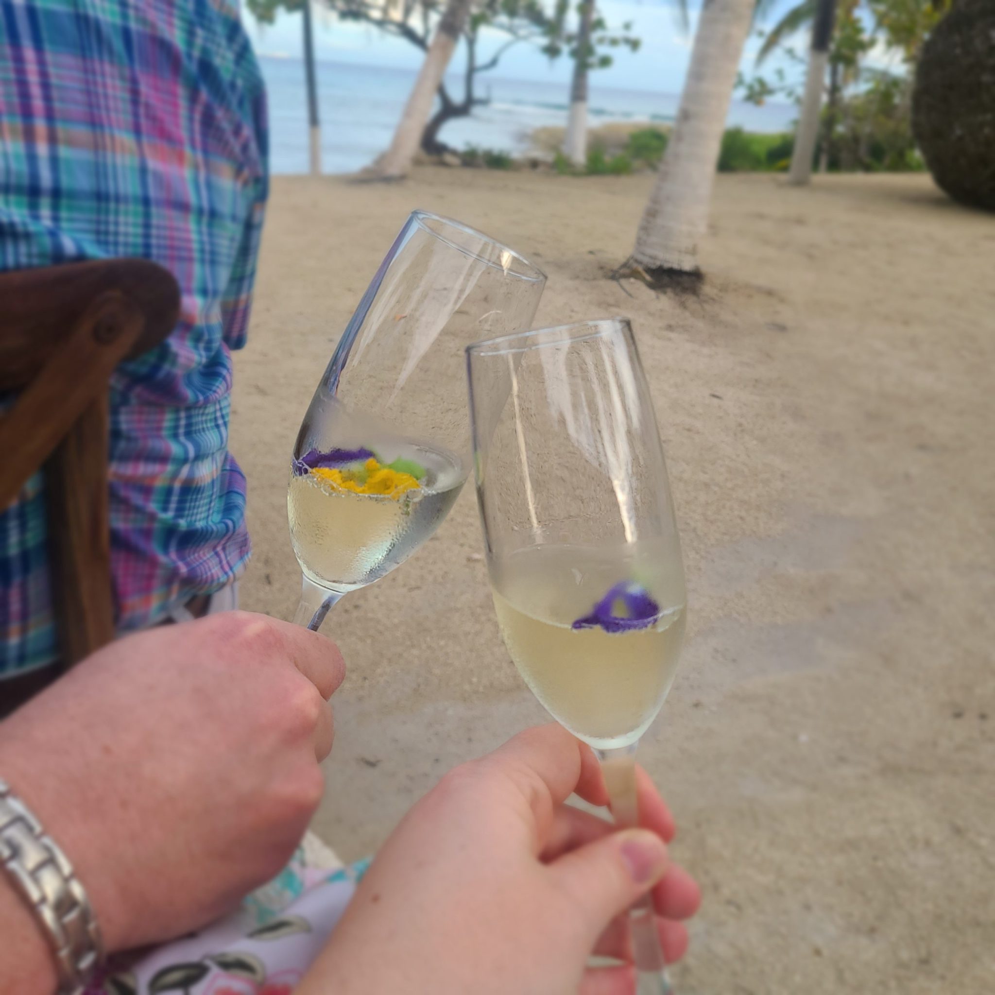Champagne cheers with flowers on beach
