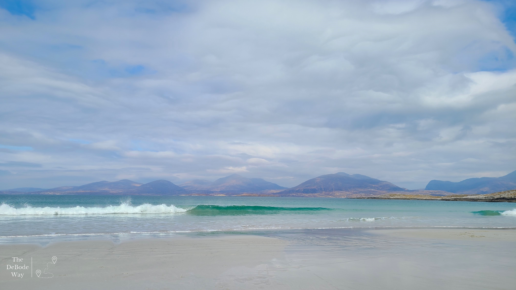 Crashing waves on sandy Luskentyre Beach with mountains behind