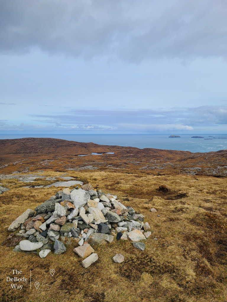 Pile of rocks in foreground with moor leading to the sea at the top
