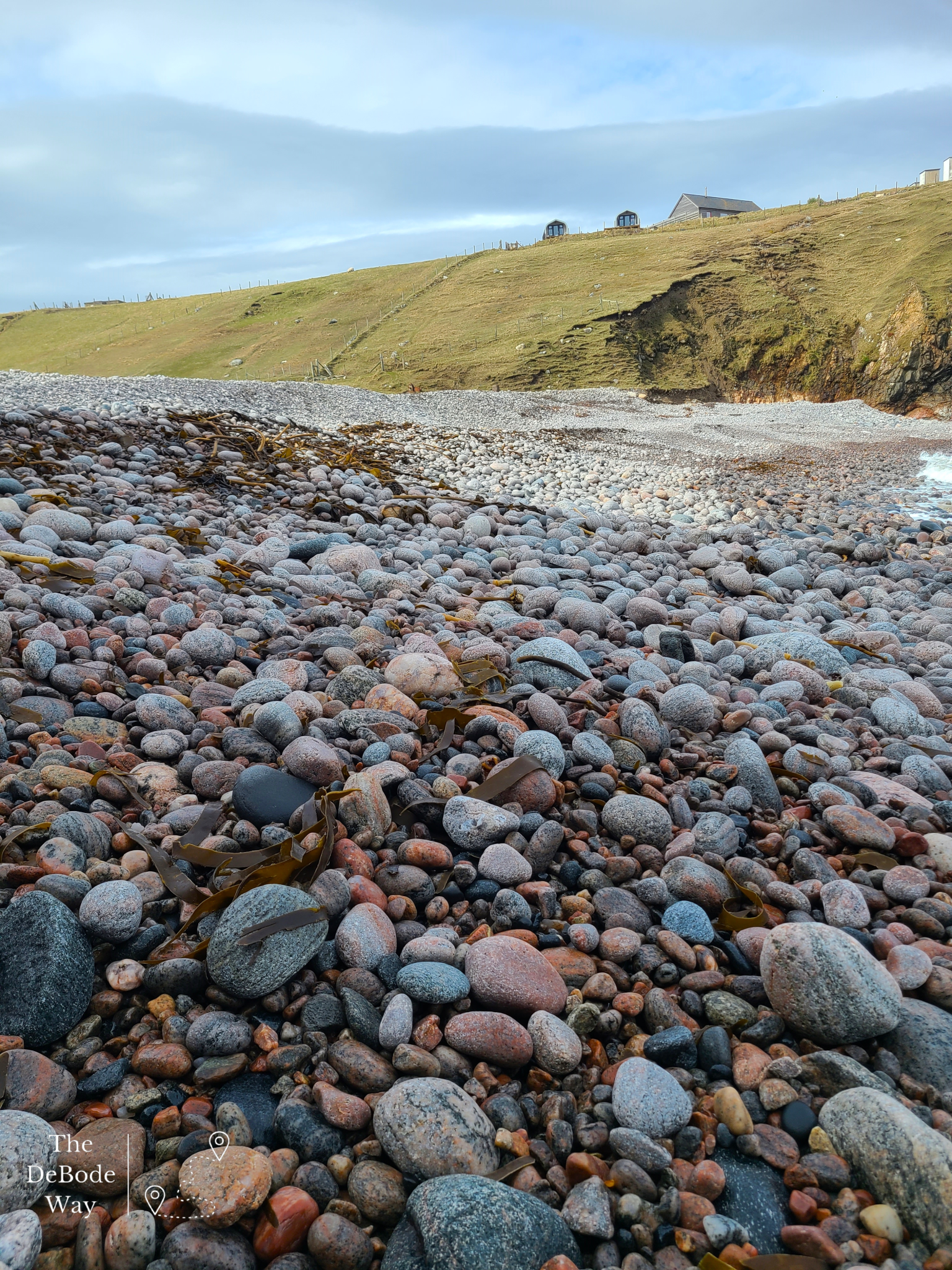 Colorful round sea rocks at the bottom of grassy cliff