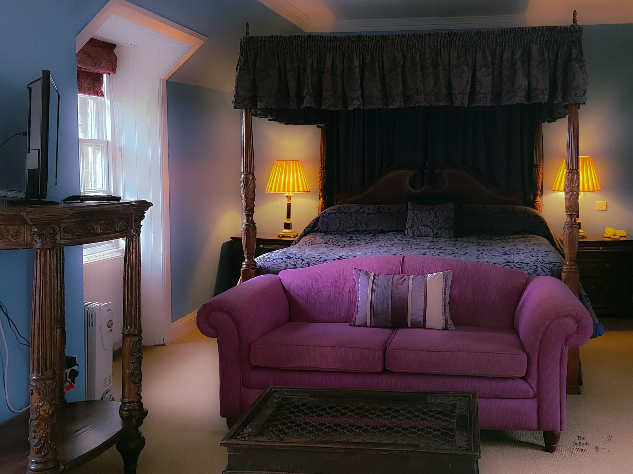Hotel room with a purple couch and purple canopy bed