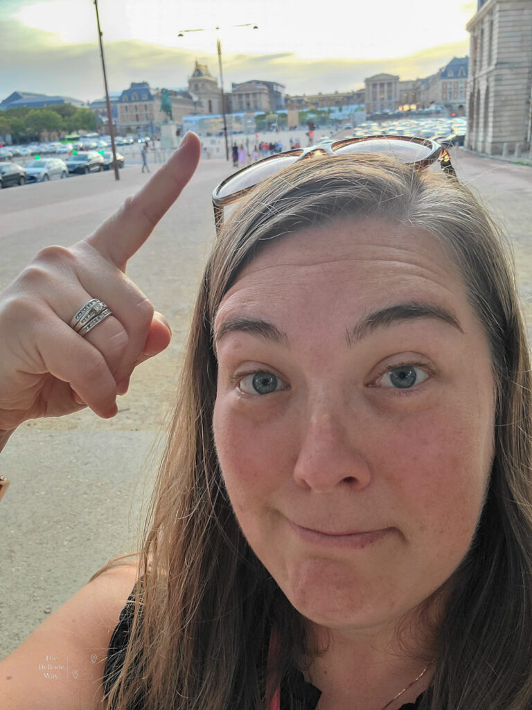 Tasha outside the hotel pointing at the Palace of Versailles