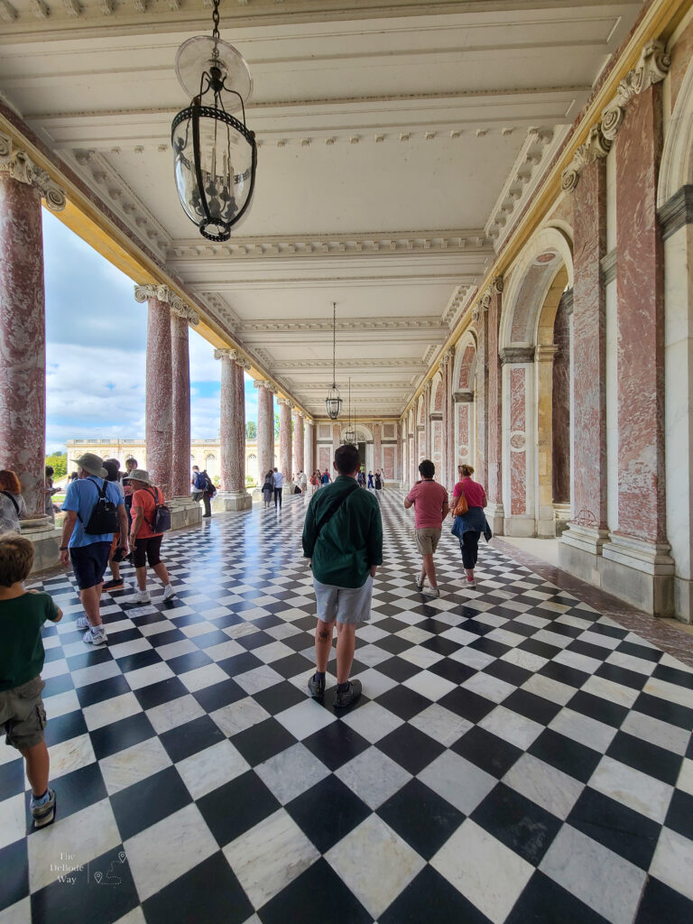 Jason in the black and white checkered walkway between wings at the Grand Trianon