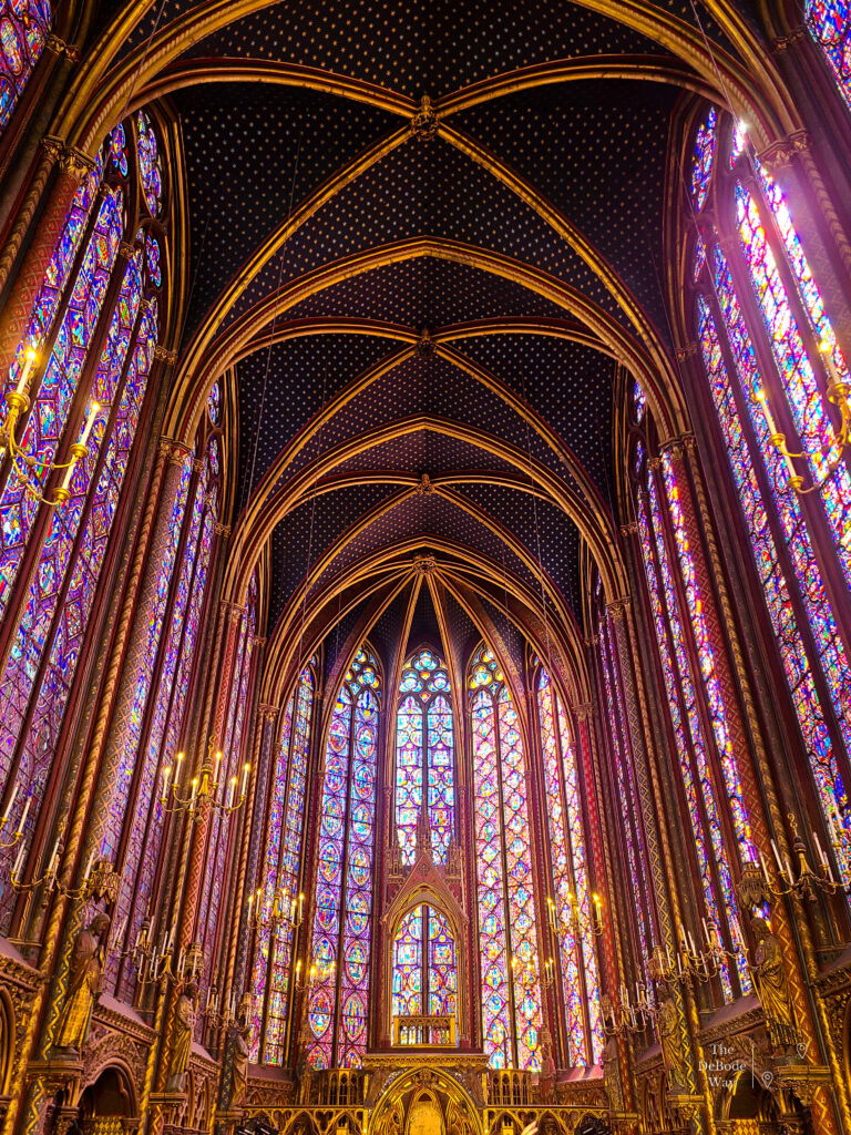 A starry night sky ceiling surrounded by a rainbow of stained glass windows in Sainte Chapelle - alter end of the upper chapel