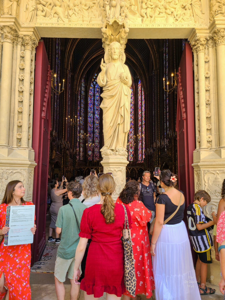 Group of people entering through the ornate doorways of the upper chapel of Sainte Chapelle