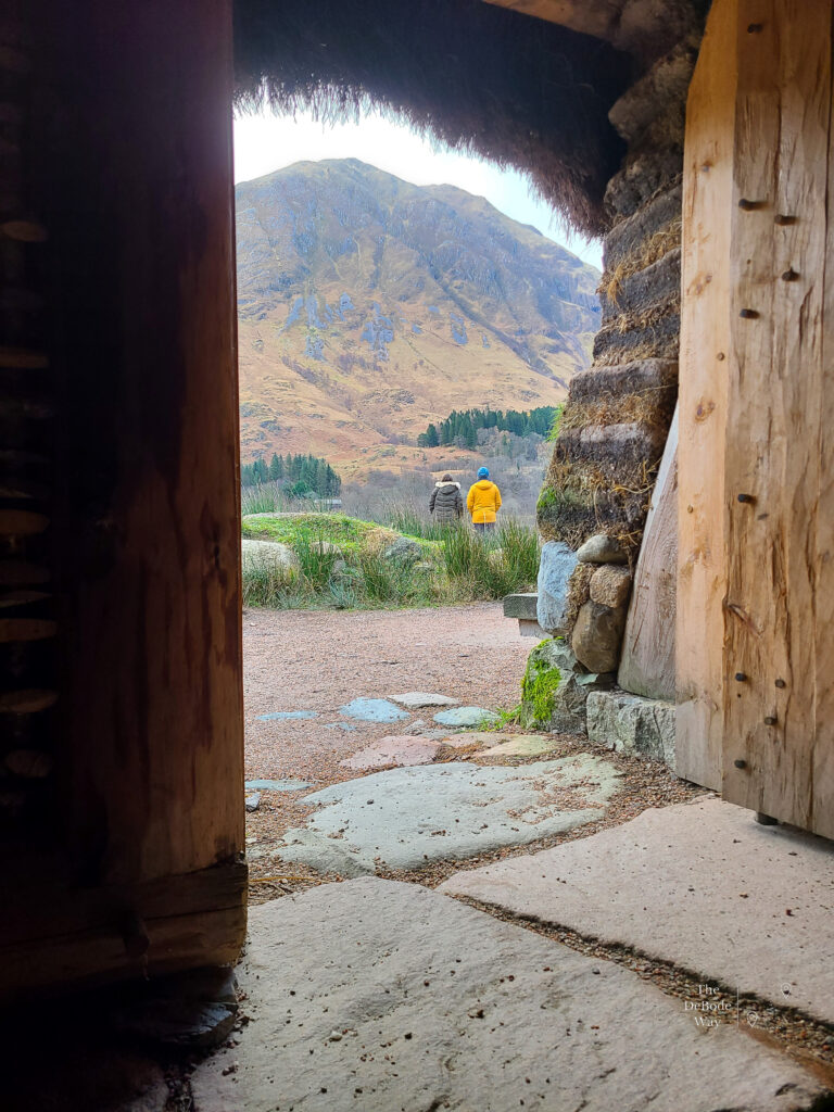 Jason and Sandy framed by the entrance of the turf house with Glencoe in the background