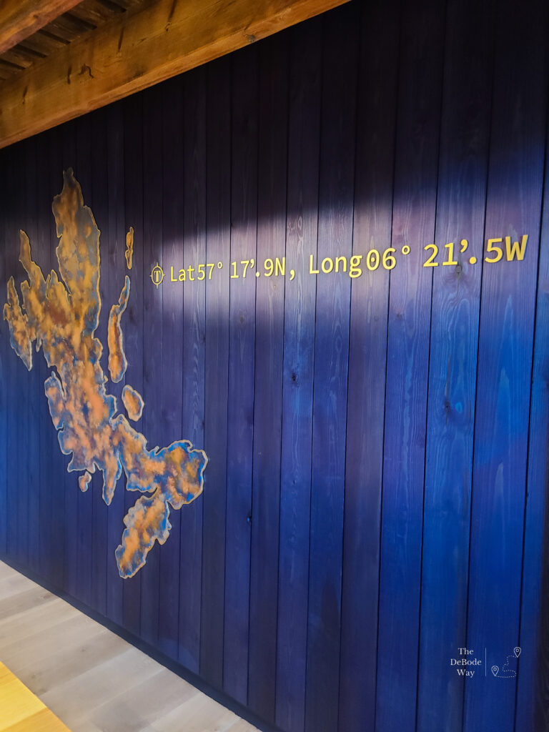 Blue slat wall with a brown cutout of the Isle of Skye and the Lat & Long of Talisker Distillery
