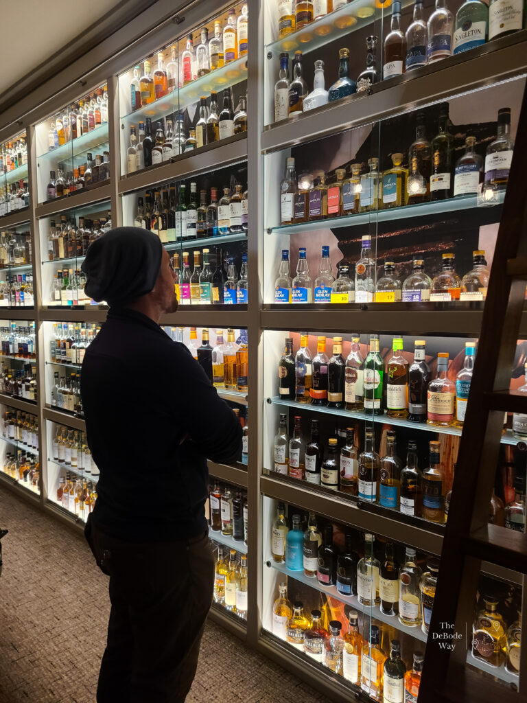 Jason admiring a wall of whisky bottles at Dowans Hotel in Arberlour Scotland