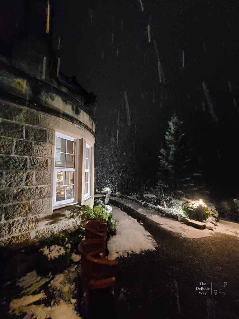 It's snowing in the dark outside the stone Dowans Hotel in Arberlour, Scotland