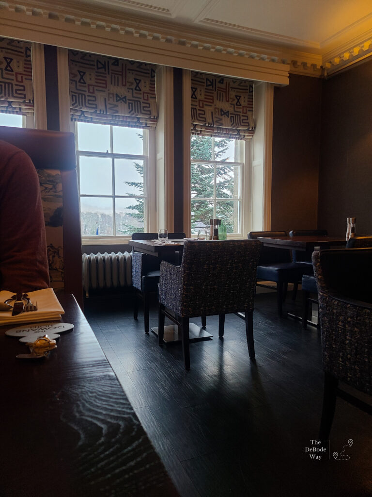 The snowy view through the windows, beyond the tables and chairs at breakfast at Dowans Hotel
