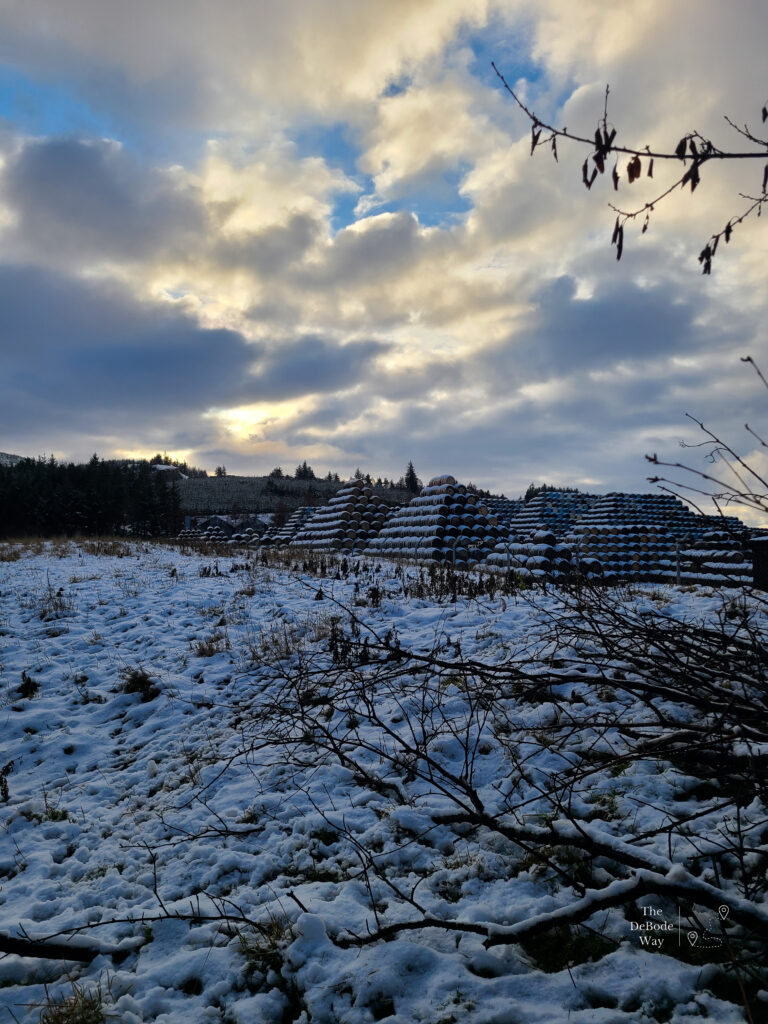 Giant pyramids of casks stacked in the yard, covered in snow