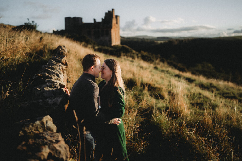 Jason and Tasha in the Scottish Borders by a stone wall near a castle ruin