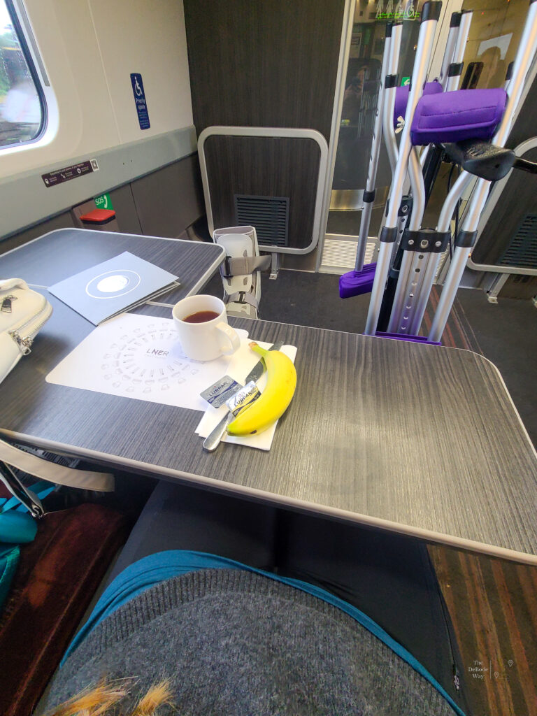 Seated in the disabled travel area of the LNER train with tea and a banana