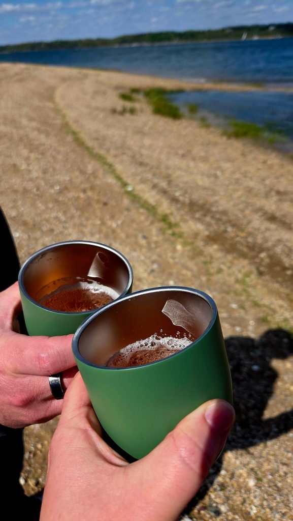 Cheers in green travel cups on the beach near Oyster Bay